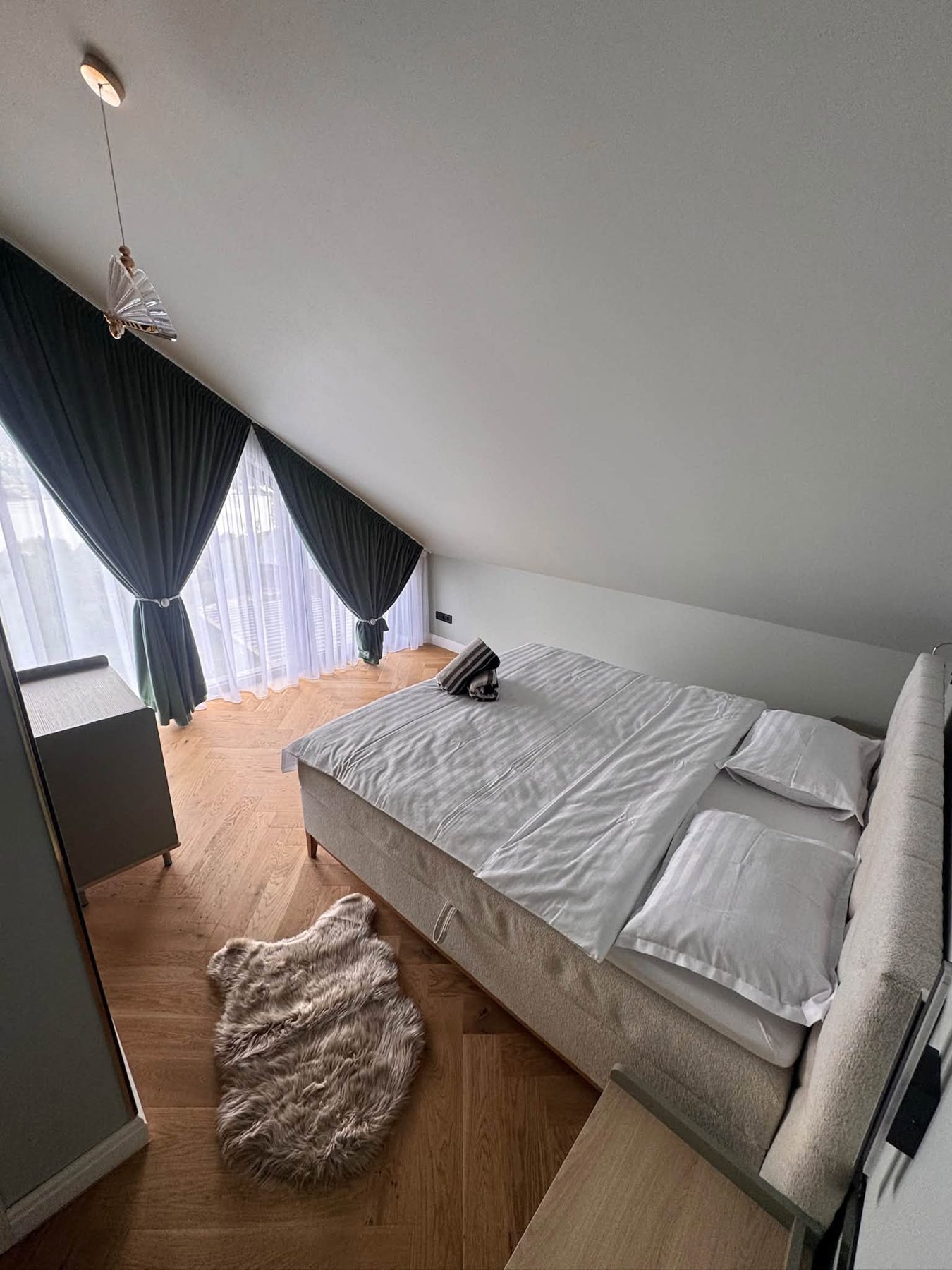 Dormitor la mansardă cu draperii verzi și parchet din stejar