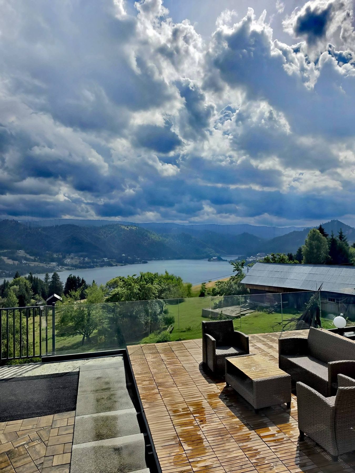 Terasa cu mobilier din ratan și priveliște spre munți și lac